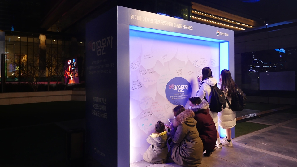 서울 삼성역 코엑스 광장에 ‘긴급마음문자’ 캠페인의 일환으로 마련된 메시지월에 시민들이 감사·응원 메시지를 남기고 있다.   
<br/>
* ‘긴급마음문자’ 캠페인은 문화체육관광부가 코로나19로 어려움을 겪는 국민에게 위로와 감사의 마음을 전하고자 기획한 것으로, 지난해 12월 1일부터 22일까지 온라인 국민 메시지 참여 행사를 진행했다. 여기에 참여한 국민의 메시지를 선정해 3차원 실감형 영상으로 제작하고 서울 삼성역(코엑스 광장) 일대 5대의 대형 옥외전광판에 송출하고 있다. 해당 영상은 이달 23일까지 볼 수 있다. 