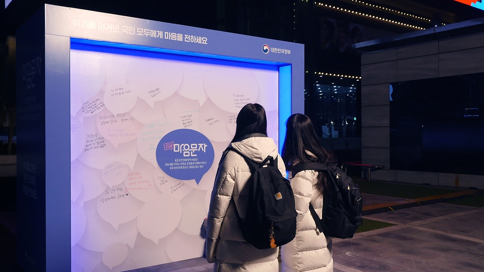 서울 삼성역 코엑스 광장에 ‘긴급마음문자’ 캠페인의 일환으로 마련된 메시지월에 시민들이 감사·응원 메시지를 남기고 있다.   
<br/>
* ‘긴급마음문자’ 캠페인은 문화체육관광부가 코로나19로 어려움을 겪는 국민에게 위로와 감사의 마음을 전하고자 기획한 것으로, 지난해 12월 1일부터 22일까지 온라인 국민 메시지 참여 행사를 진행했다. 여기에 참여한 국민의 메시지를 선정해 3차원 실감형 영상으로 제작하고 서울 삼성역(코엑스 광장) 일대 5대의 대형 옥외전광판에 송출하고 있다. 해당 영상은 이달 23일까지 볼 수 있다. 