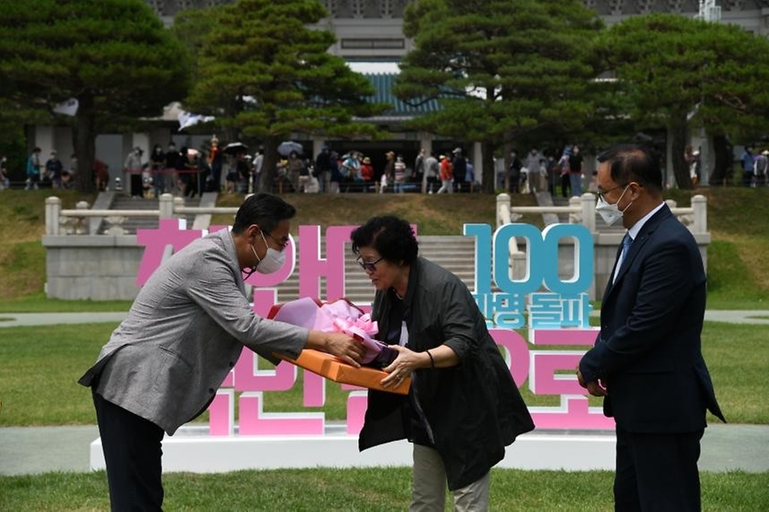 문화재청 청와대국민개방추진단 김명준 과장이 청와대 개방 44일째인 22일 서울 종로구 청와대 대정원에서 개최한 ‘100만 번째 청와대 관람객’ 기념행사에서 주인공으로 선정된 김영순 씨에게 꽃다발과 기념품을 전달하고 있다.