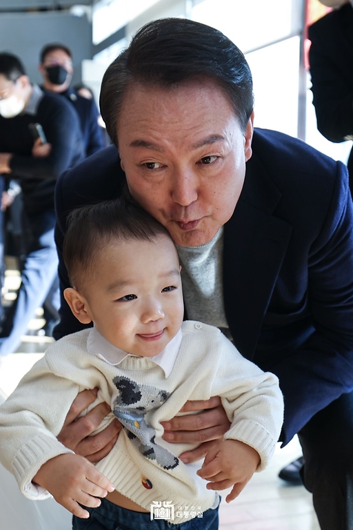 윤석열 대통령이 17일 주민들에게 감사 인사를 하기 위해 서울 서초구 아크로비스타 사저를 찾아 어린이를 안고 있다. 