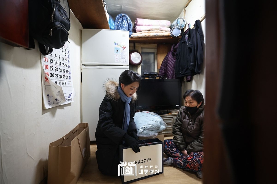 김건희 여사가 22일 ‘2022 찾아가는 성탄절 희망박스 나눔행사’를 위해 서울 용산구 남대문쪽방촌을 찾아 어르신에게 겨울 점퍼를 선물하고 있다. 