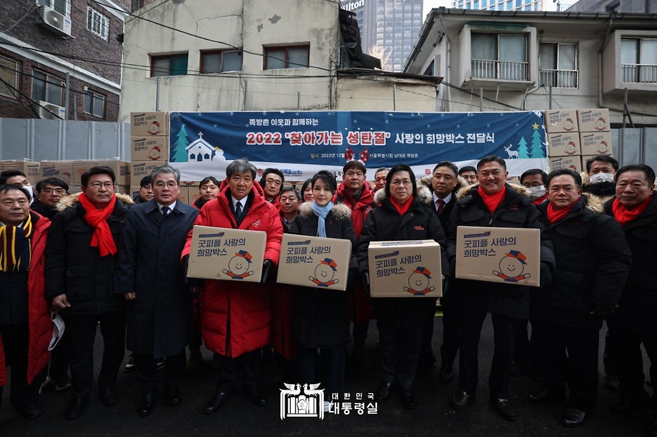 김건희 여사가 22일 서울 용산구 남대문쪽방촌에서 열린 ‘2022 찾아가는 성탄절 희망박스 나눔행사’에서 자원봉사자들과 함께 희망박스를 들고 기념 촬영하고 있다.