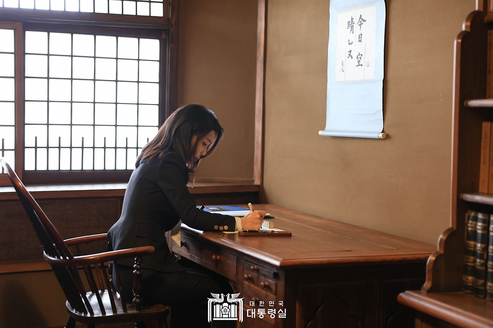 김건희 여사가 17일 일본 도쿄 민예관에서 설립자인 야나기 무네요시가 생전 사용했던 책상에 앉아 방명록을 작성하고 있다.