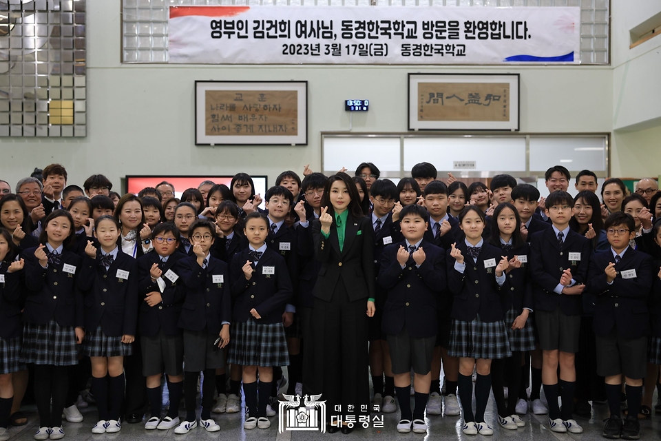 김건희 여사가 17일 일본 도쿄 동경한국학교에서 재학생들과 손가락 하트 포즈를 취하며 기념촬영을 하고 있다. 