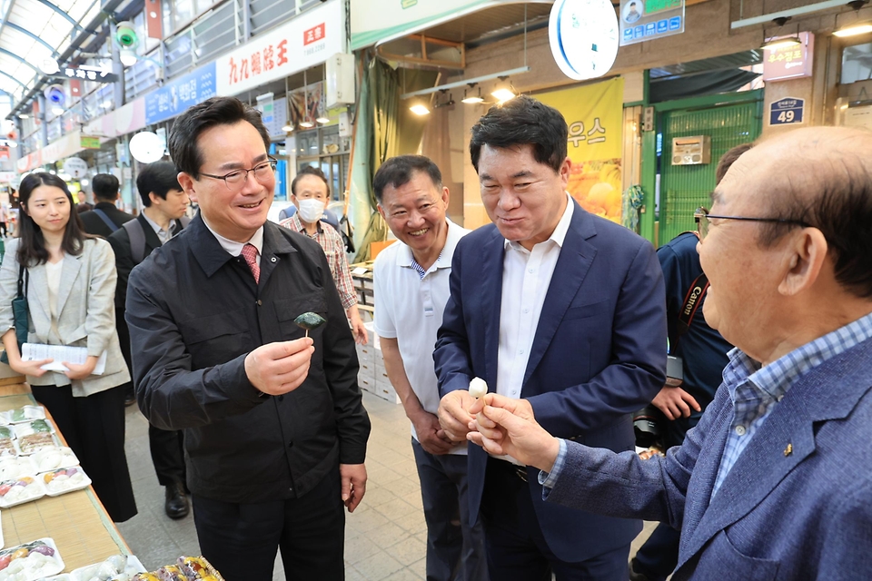 정황근 농림축산식품부 장관이 25일 서울 관악구 관악신사시장을 방문해 송편을 시식하며 관계자와 대화하고 있다.