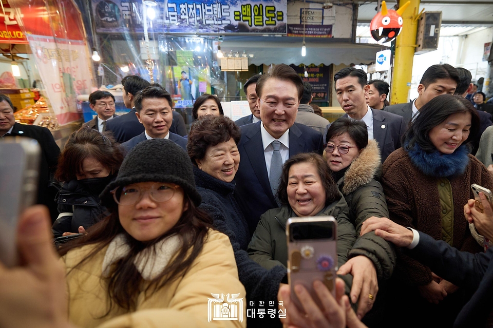 윤석열 대통령이 8일 서울 광진구 중곡제일시장을 방문해 시민들의 셀카 촬영 요청에 응하고 있다.