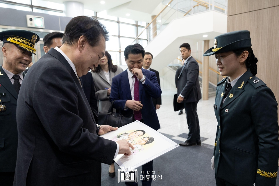 윤석열 대통령이 28일 충북 괴산군 육군학생군사학교에서 2024년 학군장교 임관식을 마친 뒤 학군가족 간담회에 참석해 임관 장교로부터 그림 선물을 받고 있다. 