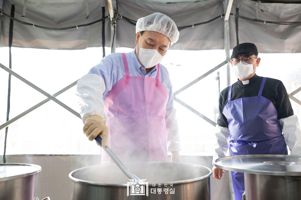 윤석열 대통령이 27일 서울 명동성당 내 무료 급식소인 ‘명동밥집’에서 명동밥집 센터장 백광진 신부와 김치찌개를 조리하고 있다.