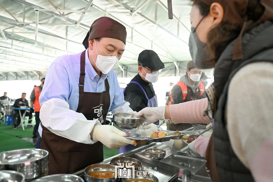 윤석열 대통령이 27일 서울 명동성당 내 무료 급식소인 ‘명동밥집’에서 봉사활동을 펼치며 급식장 내 빈 테이블에 놓을 식판에 배식을 받고 있다.