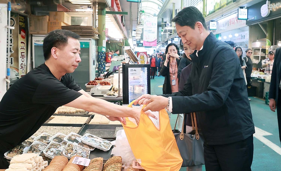 안덕근 산업통상자원부 장관이 14일 서울 망원시장을 방문해 시장 내 점포를 둘러보며 물품을 구매하고 있다.