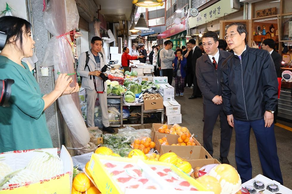 한덕수 국무총리가 20일 서울 종로구 통인시장을 방문해 점포를 돌아보며 과일을 구매하고 있다. 