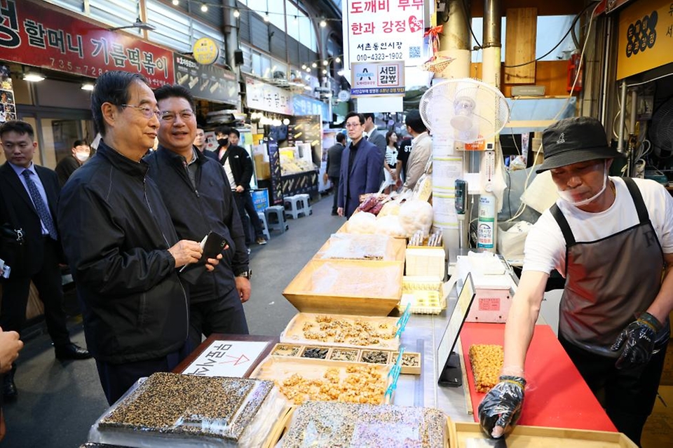 한덕수 국무총리가 20일 서울 종로구 통인시장을 방문해 점포를 돌아보며 강정을 구매하고 있다. 