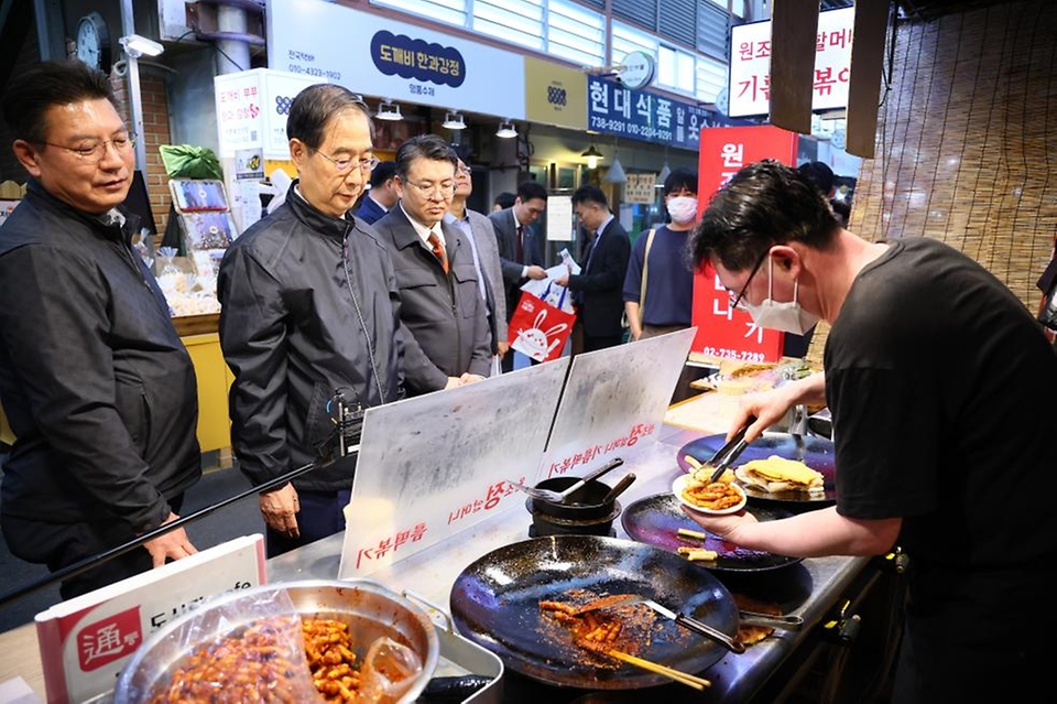 한덕수 국무총리가 20일 서울 종로구 통인시장을 방문해 점포를 돌아보며 떡볶이를 구매하고 있다.