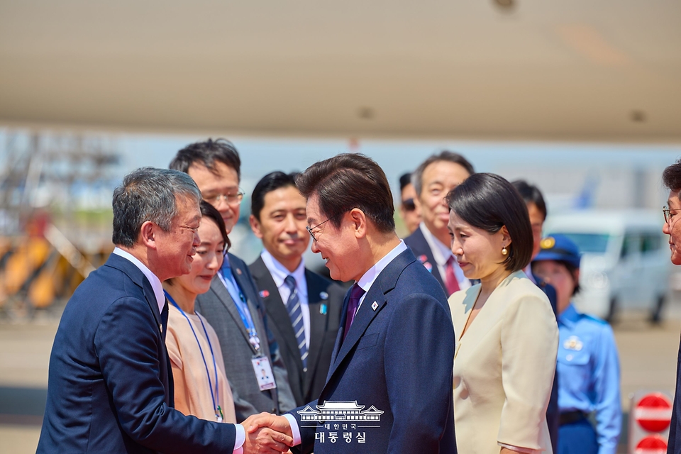 이재명 대통령과 김혜경 여사가 23일(현지시간) 일본 도쿄 하네다 국제공항에서 영접 관계자들과 인사하고 있다. 
