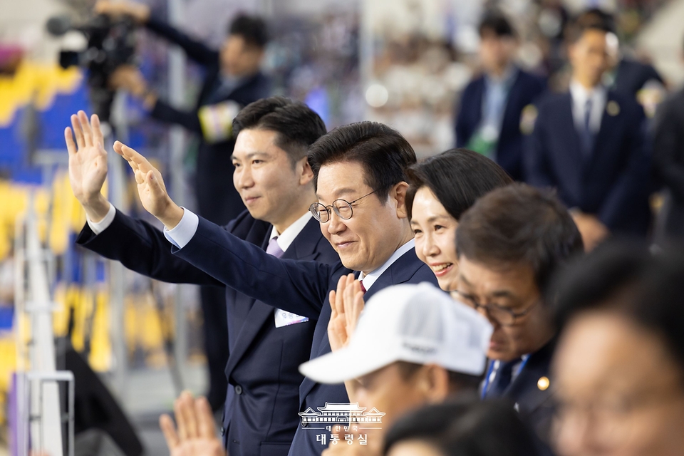 이재명 대통령과 김혜경 여사가 17일 부산아시아드주경기장에서 열린 제106회 전국체육대회 개막식에서 선수단 입장을 지켜보며 인사하고 있다.