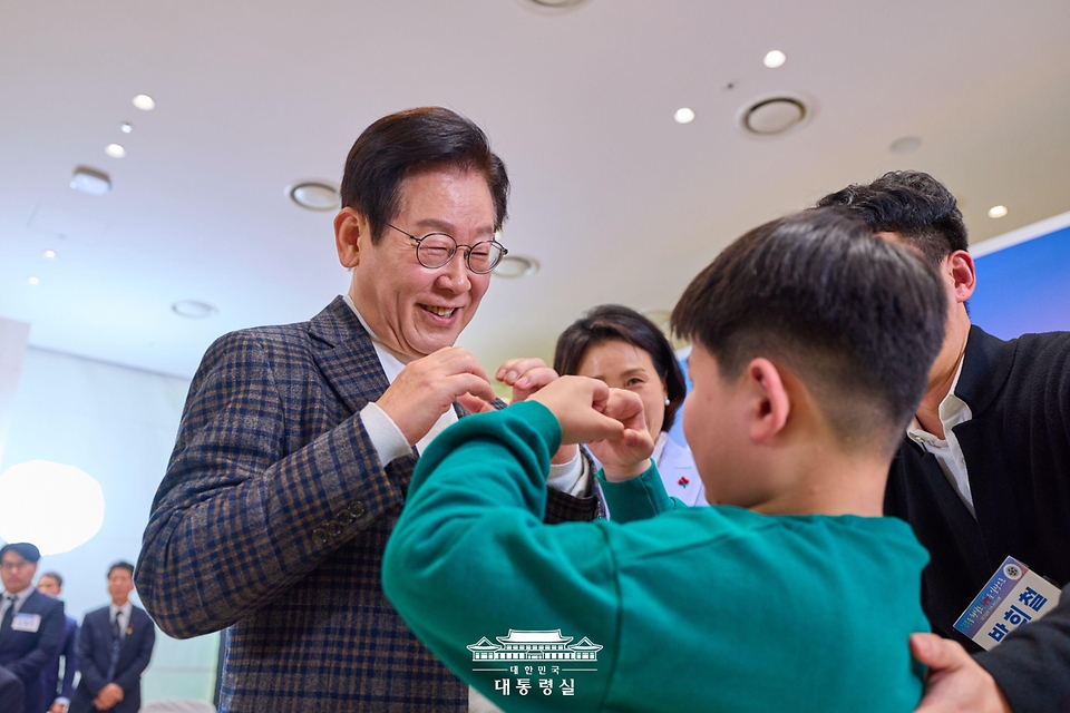 이재명 대통령이 24일 서울 서대문구 신촌세브란스 연세암병원 중입자치료센터에서 열린 희귀질환 환우·가족 간담회를 마친 후 어린이에게 손하트를 그려보이고 있다.