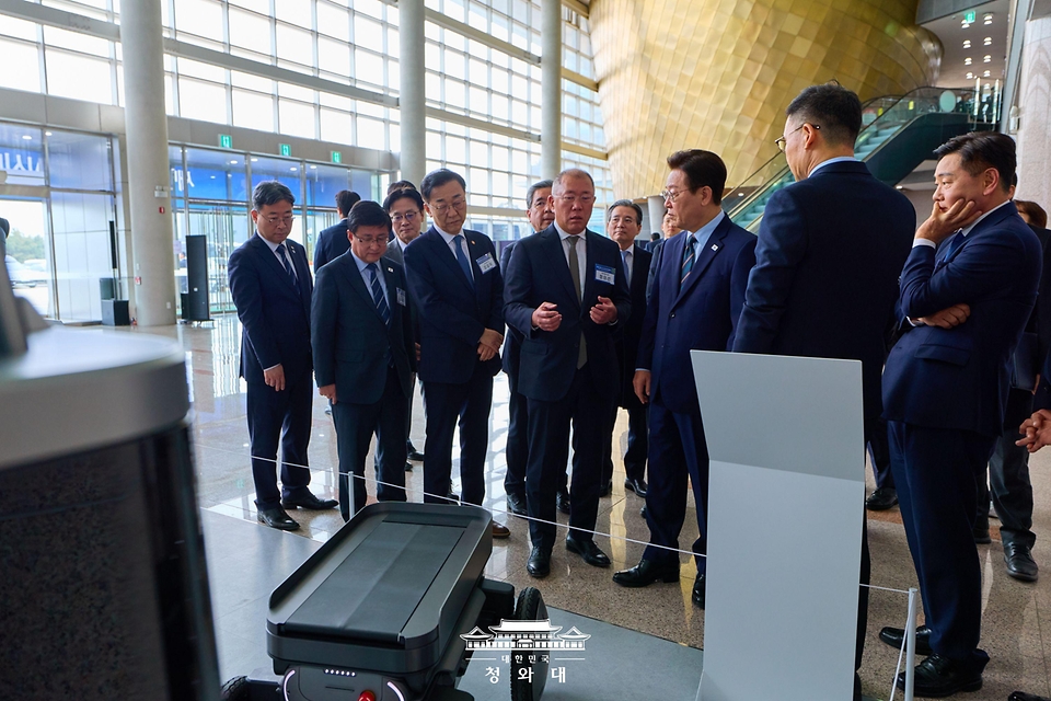 이재명 대통령이 2월 27일 전북 군산시 새만금 컨벤션센터에서 열린 새만금 로봇·수소·AI 시티 투자협약식에서 자율주행휠로봇(MobED)에 대한 설명을 듣고 있다.