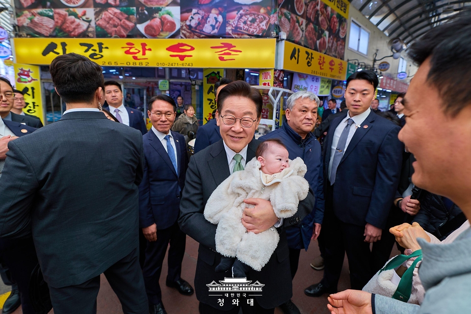 이재명 대통령이 3월 13일 충북 청주시 서원구 사창시장을 찾아 아이를 안고 인사를 하고 있다.