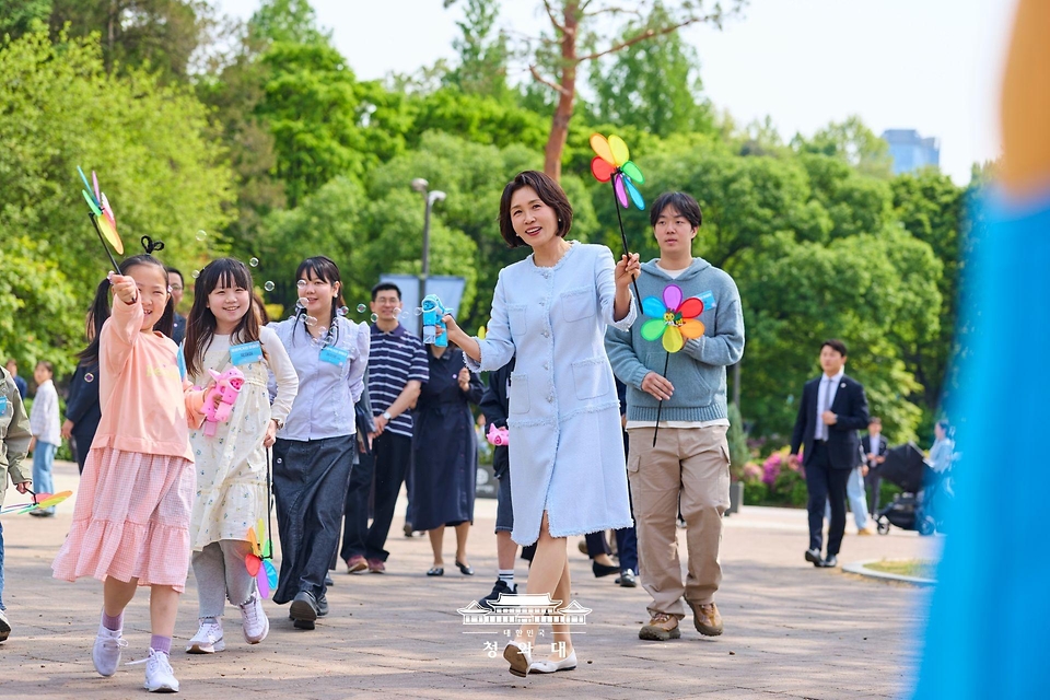 김혜경 여사가 4월 29일 서울 어린이대공원에서 열린 당원병 환아의 건강한 식생활을 위한 희망쿠키 굽기 행사에서 참석한 아이들과 산책을 하며 비누방울 놀이를 하고 있다.