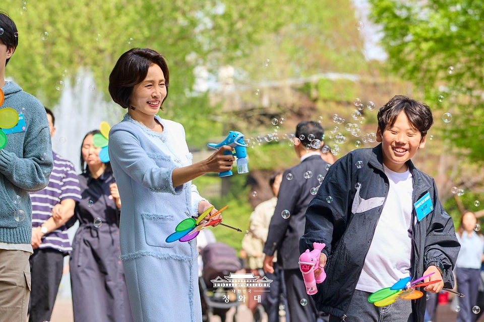 김혜경 여사가 4월 29일 서울 어린이대공원에서 열린 당원병 환아의 건강한 식생활을 위한 희망쿠키 굽기 행사에서 참석한 아이들과 산책을 하며 비누방울 놀이를 하고 있다.