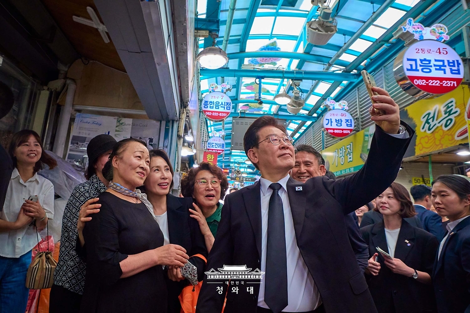 이재명 대통령과 김혜경 여사가 5월 18일 광주 동구 남광주시장을 찾아 시민들과 기념 촬영을 하고 있다.