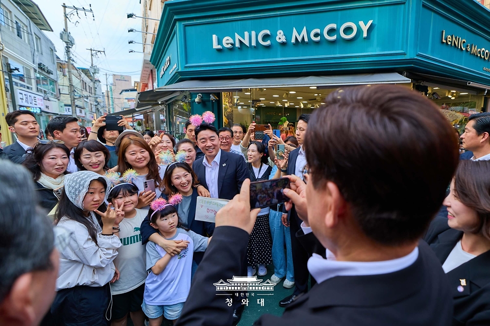 이재명 대통령이 5월 18일 경북 안동구시장에서 강훈식 비서실장과 시민들의 사진을 찍어주고 있다.