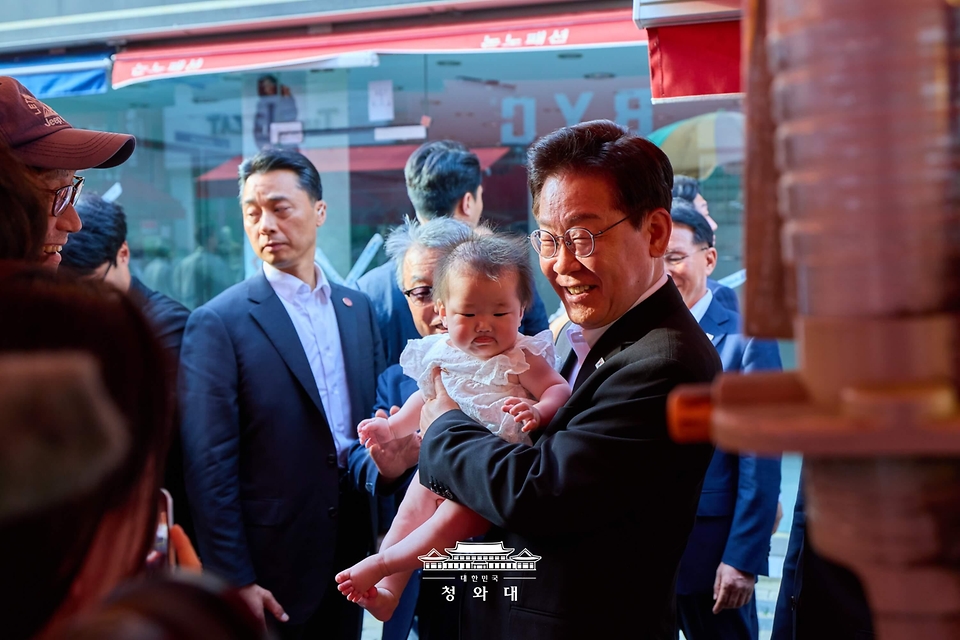 이재명 대통령이 5월 18일 경북 안동구시장을 찾아 아이와 기념 촬영을 하고 있다.