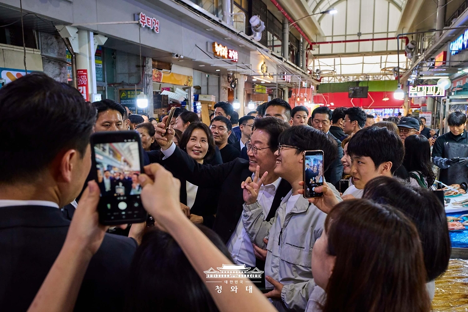 이재명 대통령과 김혜경 여사가 5월 23일 경남 김해 외동전통시장을 방문해 시민들과 기념촬영을 하고 있다.