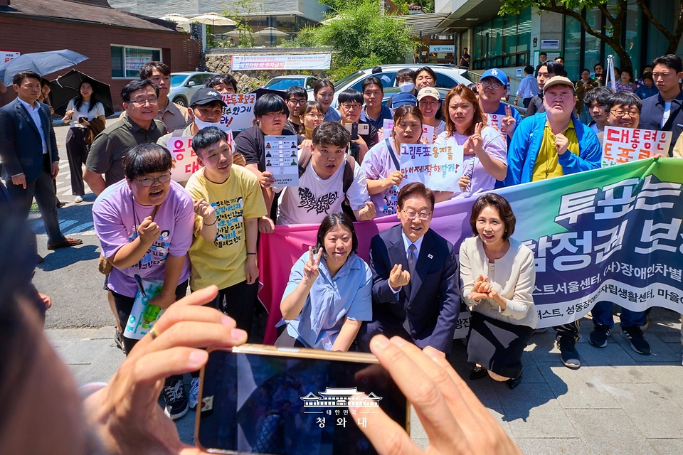 이재명 대통령과 김혜경 여사가 제9회 전국동시지방선거 사전투표 첫날인 5월 29일 서울 종로구 삼청동 주민센터 사전투표소 앞에서 발달장애인 참정권 보장 촉구 장애인단체 관계자들의 의견을 청취한 뒤 함께 기념 촬영을 하고 있다.