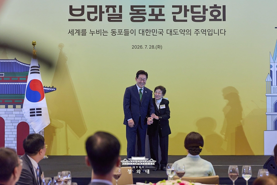 이재명 대통령이 7월 28일(현지 시간) 브라질 상파울루 한 호텔에서 열린 동포 오찬간담회에서 고 한응규 애국지사의 부인 김가균씨에게 감사패를 전달한 뒤 기념 촬영을 하고 있다.