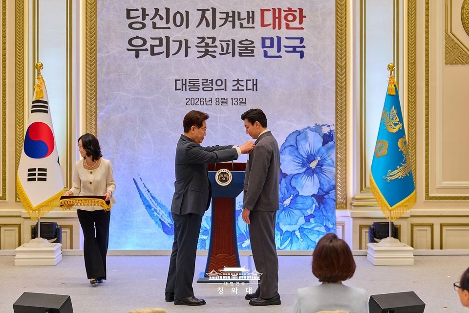 이재명 대통령이 8월 13일 청와대 영빈관에서 열린 국가유공자 및 보훈 가족 초청 오찬에서 재외 독립유공자 후손인 김막심 씨에게 태극기 배지를 달아주고 있다.