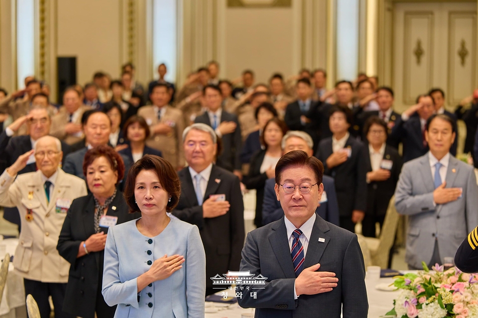 이재명 대통령과 김혜경 여사가 8월 13일 청와대 영빈관에서 열린 국가유공자 및 보훈 가족 초청 오찬에서 국기에 경례하고 있다.