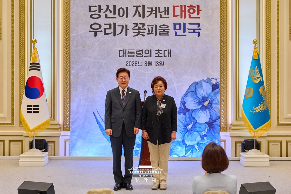 이재명 대통령이 8월 13일 청와대 영빈관에서 열린 국가유공자 및 보훈 가족 초청 오찬에서 5·18민주유공자 고 정동년 선생의 배우자 이명자 씨에게 태극기 배지를 달아준 뒤 기념촬영을 하고 있다.