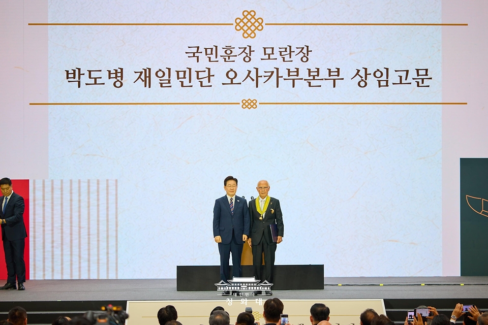 이재명 대통령이 9월 28일 인천 송도에서 열린 제20회 세계한인의 날 기념식에서 박도병 재일민단 오사카부본부 상임고문에게 모란장을 수여한 후 기념촬영을 하고 있다.