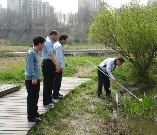 장순식 팀장(왼쪽 두번째)이 생태연못에서 직원들과 모기 유충을 관찰하고 있다.　