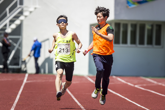 19일 강릉종합경기장에서 진행된 제10회 전국장애학생체육대회 육상 남자 200m T11, T12(시각장애) 고등부 경기에 참가한 선수가 가이드와 함께 결승선을 향해 힘껏 질주하고 있다. (사진=대한장애인체육회 제공)