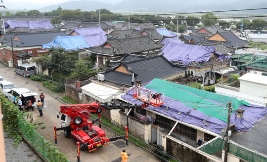 경주시 관계자들이 18일 오전 지진피해를 입은 경북 경주시 사정동 주택 기와에 비를 피할 수 있는 천막과 그물을 씌우고 있다. (사진=저작권자(c) 연합뉴스, 무단 전재-재배포 금지)