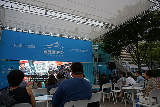 김성균 감독의 오프닝 영상을 시청하는 시민들