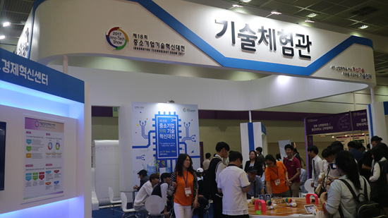 기술 체험관에서 스마트 로봇을 이용한 토너먼트 게임을 즐기는 사람들.