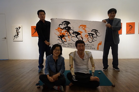 퍼포먼스 때 그린 그림을 들고 기념사진을 촬영하고 있는 석 화백.