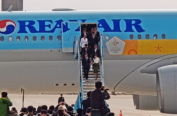 문이 열리고 성화를 가져온 인수단이 나오고 있다.
