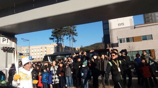 20번째 주자가 세종시민들의 응원을 받으며 성화를 들고 달리고 있다.