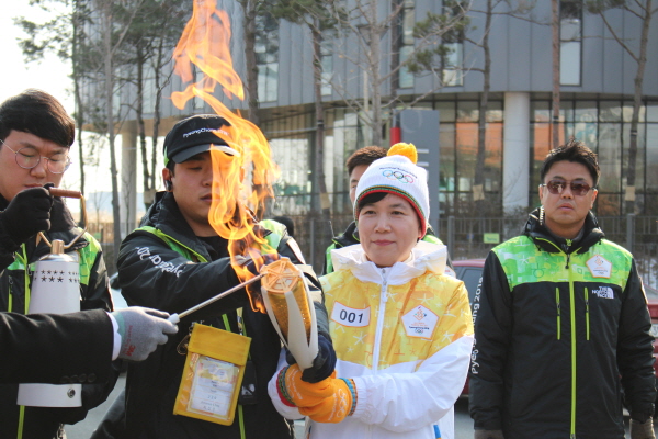 성화봉에 불을 붙이고 있습니다.
