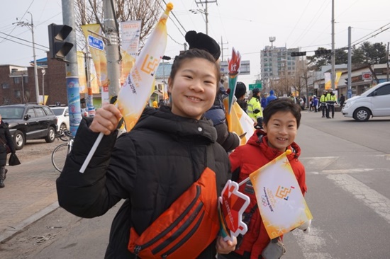 이평사거리에서 성화봉송 주자를 기다리며 깃발을 흔드는 초등생 남매.