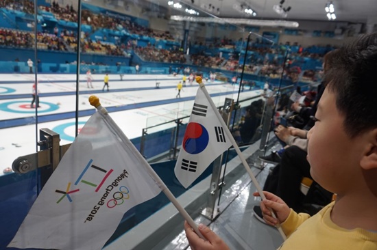 남자 컬링 경기를 보며 태극기 들고 대한민국을 응원하는 초등학생 아이 모습