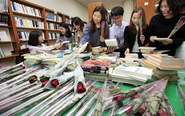 23일 광주 북구청 행정자료실에서 열린 세계책의 날 기념 책드림 행사에서 책을 빌리러온 직원들이 책과 장미꽃을 고르고 있다.(출처=뉴스1, 광주 북구 제공)