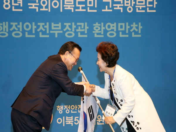 국외이북도민 고국방문단 대표 남혜영씨에게 태극기를 전달하고 있다. <사진=이북5도위원회>