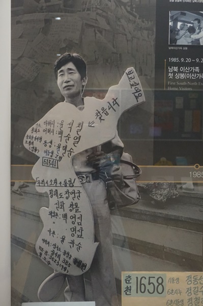 (이산가족을 찾기 위해 이름을 새기고 서있는 중년 남성의 모습)