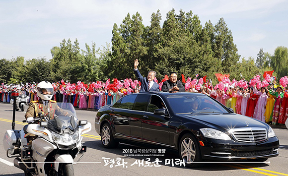 문재인 대통령과 김정은 국무위원장이 무개차를 함께 타고 순안공항에서 백화원 영빈관으로 이동하고 있다. ⓒ 평양사진공동취재단