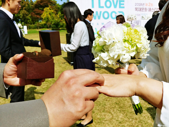 목혼식에 참석한 부부가 직접 만든 나무반지를 교환하고 있다